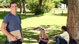 Video: Man waving towards his friends who are sitting behind him before he looks at the camera Man waving towards his friends who are sitting behind him before he looks at the camera