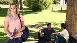 Video: Woman waving towards her friends who are sitting behind her before she looks at the camera Woman waving towards her friends who are sitting behind her before she looks at the camera