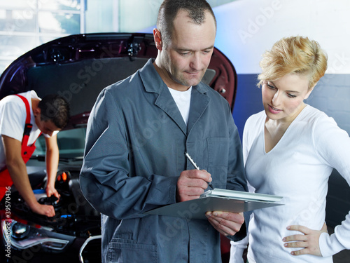 Foto: Master mechanic explaining repair costs to customer in garage Master mechanic explaining repair costs to customer in garage