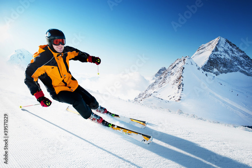 Photo: Skier in mountains, prepared piste and sunny day Skier in mountains, prepared piste and sunny day