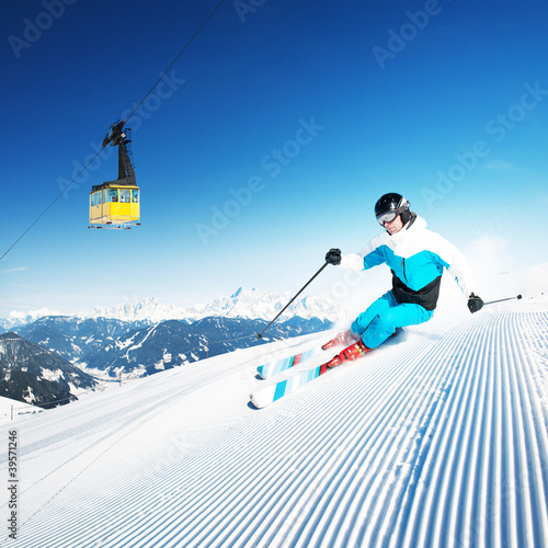 Photo: Skier in mountains, prepared piste and sunny day Skier in mountains, prepared piste and sunny day