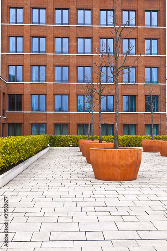 Photo: facade of modern brick building with a tree in front facade of modern brick building with a tree in front