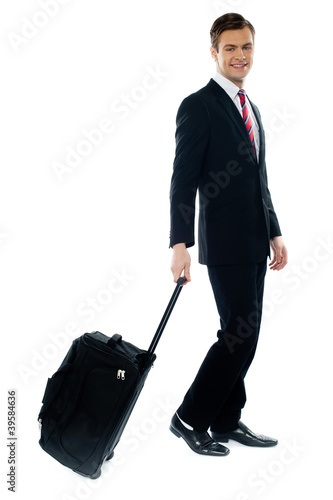 Photo: Handsome businessman dragging trolley bag Handsome businessman dragging trolley bag