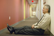 Businessman sitting on floor of hallway
