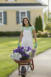 Portrait of woman with wheelbarrow full of flowers
