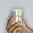 Close up of hand holding roll of dollar bills