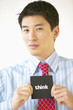 "Portrait of businessman holding ""think"" sign"