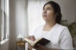 Woman praying while holding Bible