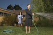 Businesswoman with garden hose in front yard