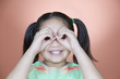 Young girl peeking out from inside curled fists