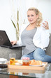 young blonde working on laptop while having breakfast