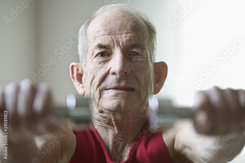 Photo: Portrait of elderly man lifting weights Portrait of elderly man lifting weights