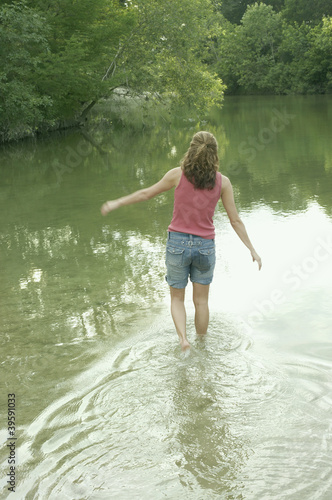 Photo: Rear view of woman walking in water Rear view of woman walking in water