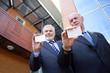 Two senior businessmen displaying their calling-cards