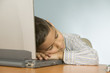Young boy asleep on laptop computer