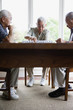 Three elderly men sitting at table playing game