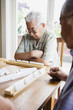 Two elderly men sitting at table playing game