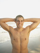 Portrait of man without shirt smiling with hands behind head