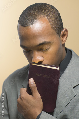 Photo: Man with eyes closed kissing Bible Man with eyes closed kissing Bible