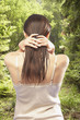 Rear view of woman standing in forest running hands through hair