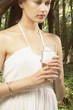 Woman holding glass of water in forest