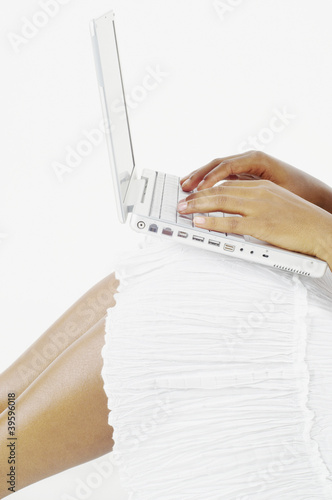 Photo: Mid section of woman balancing laptop on knees and typing Mid section of woman balancing laptop on knees and typing