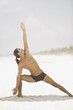 Young man doing yoga on the beach