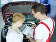 Customer and mechanic in garage checking repair costs