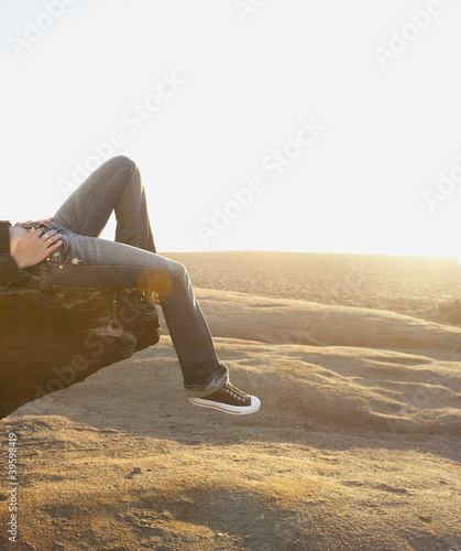 Photo: Low angle view of woman laying on log on beach Low angle view of woman laying on log on beach