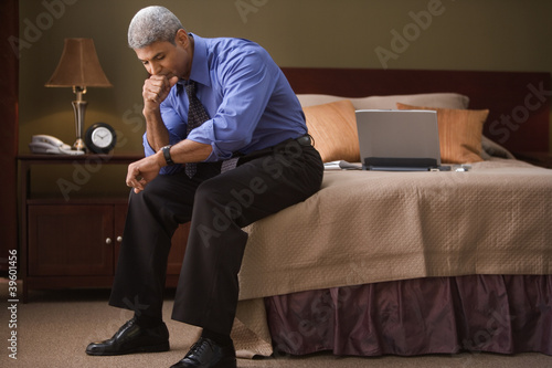 Photo: Businessman checking the time in his hotel room Businessman checking the time in his hotel room