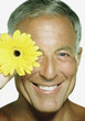 Mature man holding a sunflower by his face