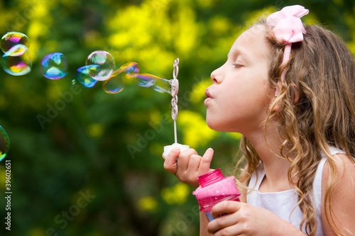 Photo: Young girl blowing bubbles. Young girl blowing bubbles.