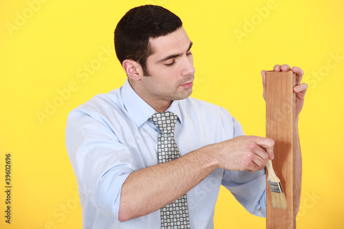 Photo: Man applying varnish to a wooden plank Man applying varnish to a wooden plank