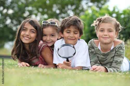 Photo: Kids playing with magnifying glass in park Kids playing with magnifying glass in park