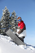 Snowboarder struggling to drag his board up the mountain