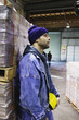 Man in warehouse leaning against pallet