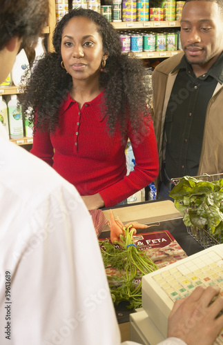Photo: African American couple at check out counter in grocery store African American couple at check out counter in grocery store