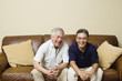 Portrait of elderly men sitting on couch laughing
