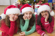 Portrait of three girls with Santa hats in front of Christmas tree