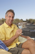 Portrait of man sitting holding wine glass at beach