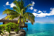 Tropical bungalow and palm tree next to amazing lagoon