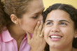 Close up of two teenage girls whispering