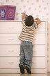 Young boy reaching on dresser