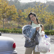 Woman carrying dry cleaning and bags of groceries to her car