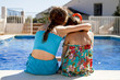 Two girls ebracing by the pool