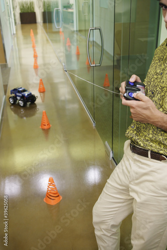 Photo: Businessman playing with an RC car in the hallway Businessman playing with an RC car in the hallway