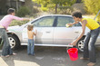 Parents with young son washing car