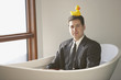 Hispanic businessman sitting in a bathtub with a rubber ducky on his head