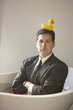 Hispanic businessman sitting in a bathtub with a rubber ducky on his head