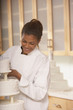African female pastry chef next to a wedding cake